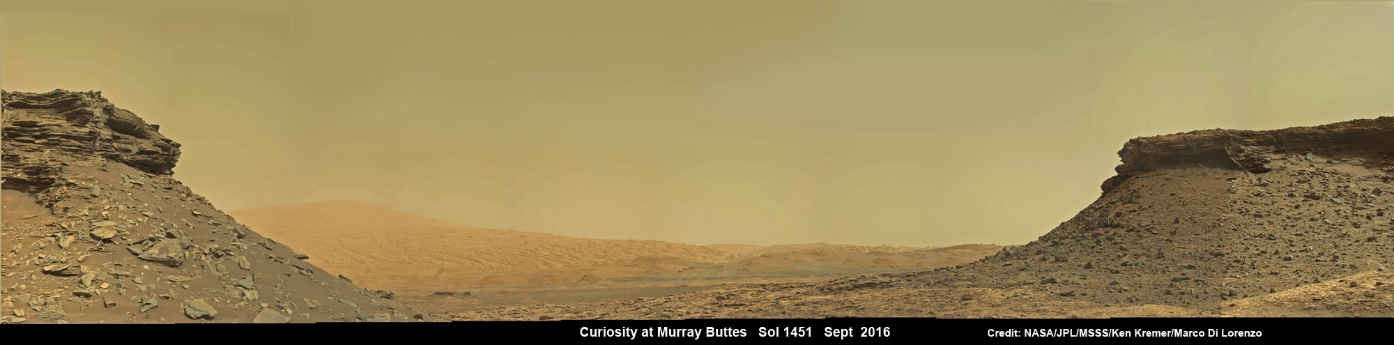 Wide angle mosaic shows lower region of Mount Sharp at center in between spectacular sloping hillsides  and layered rock outcrops of the Murray Buttes region in Gale Crater as imaged by the Mast Camera (Mastcam) on NASA's Curiosity Mars rover. This photo mosaic is stitched from Mastcam camera raw images taken on Sol 1451, Sept. 5, 2016 with added artificial sky.  Credit: NASA/JPL/MSSS/Ken Kremer/kenkremer.com/Marco Di Lorenzo