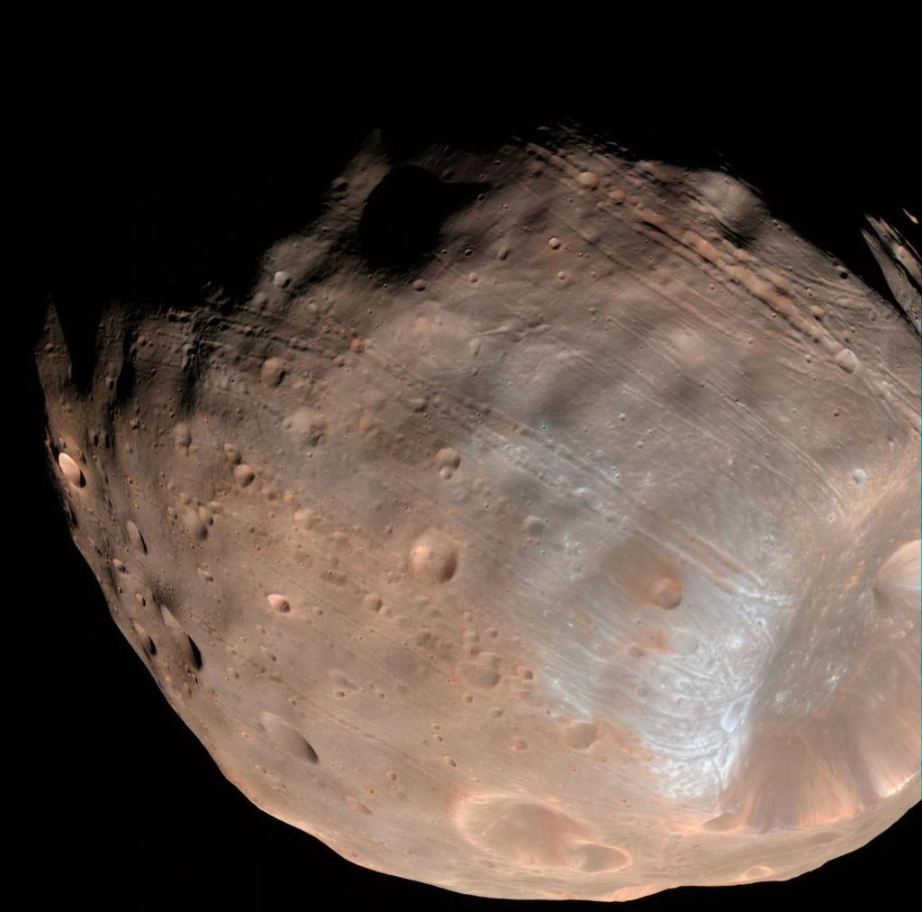 Большая часть поверхности Фобоса покрыта своеобразными линейными бороздками.  Новое исследование подтверждает идею о том, что скалы, извергающиеся из кратера Стекней (большая впадина справа), вырезали эти знаменитые канавки.  Изображение предоставлено: NASA/JPL-Caltech/Университет Аризоны.