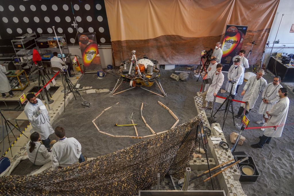 At the InSight lander test-bed facility at JPL, engineers sculpt a gravel-like material into a replica of InSight's landing site on Mars. The wood marks the boundaries of the lander's instrument placement zone. Unfortunately, the test bed can't replicate the Martian gravity and the regolith. Image Credit: NASA/JPL-Caltech/IPGP