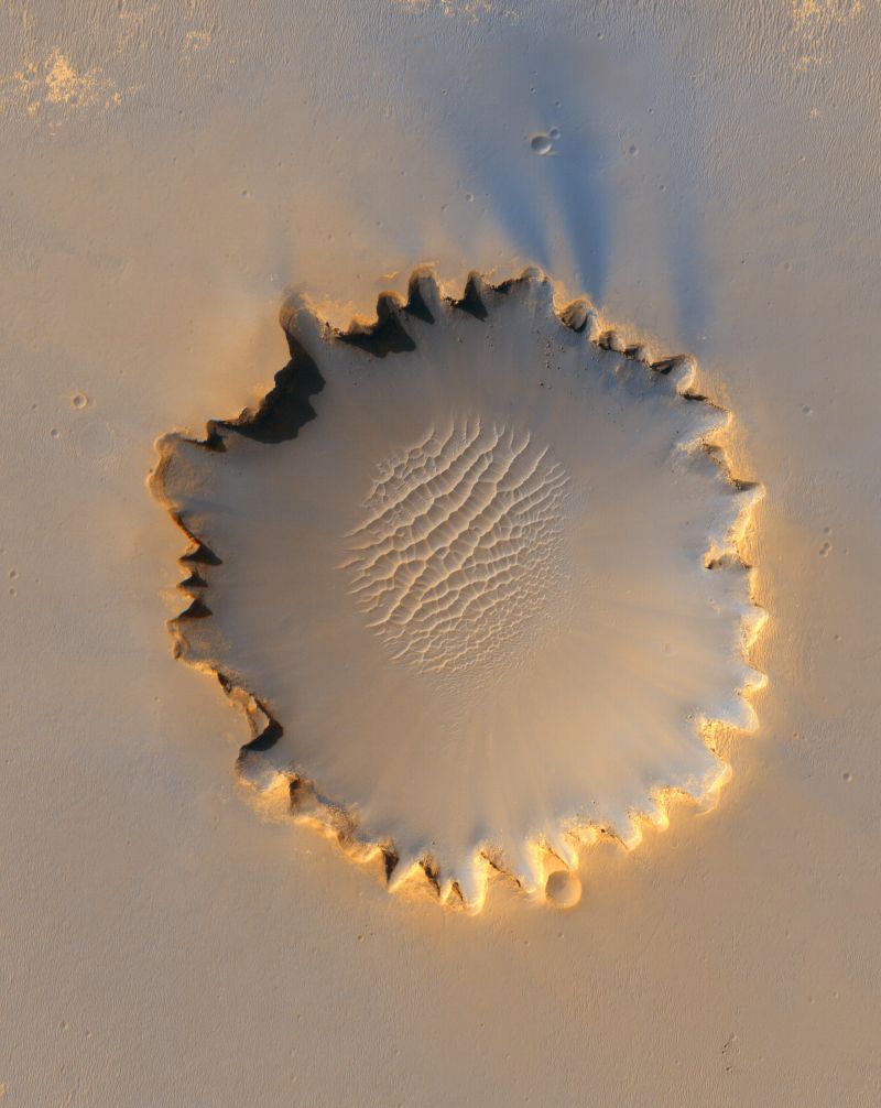A HiRISE camera image of Victoria Crater from the MRO. Opportunity is at roughly the 10 oclock position in this image, a spot that HiRISE identified as smooth enough for the rover to enter the crater. Image Credit: 
NASA/JPL-Caltech/University of Arizona/Cornell/Ohio State University
