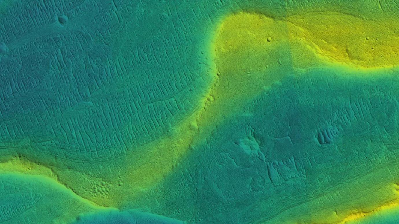 A photo of a preserved river channel on Mars. The color is overlaid to show elevation, with blue being low and yellow being high elevation. Image Credit: NASA/JPL/Univ. Arizona/UChicago
