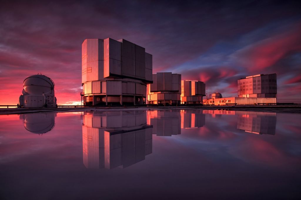 ESO’s Very Large Telescope (VLT) has recently received an upgraded addition to its suite of advanced instruments. On 21 May 2019 the newly modified instrument VISIR (VLT Imager and Spectrometer for mid-Infrared) made its first observations since being modified to aid in the search for potentially habitable planets in the Alpha Centauri system, the closest star system to Earth. This stunning image of the VLT is painted with the colours of sunset and reflected in water on the platform. While inclement weather at Cerro Paranal is unfortunate for the astronomers using it, it lets us see ESO's flagship telescope in a new light. Image Credit: ESO/VLT