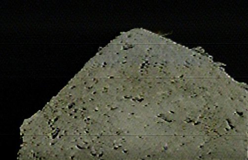  DCAM 3 captured this image of the SCI impact on 5 April 2019. The impact debris is a small spray of dust against the black of space, near the top-right limb of the asteroid. Image Credit: JAXA