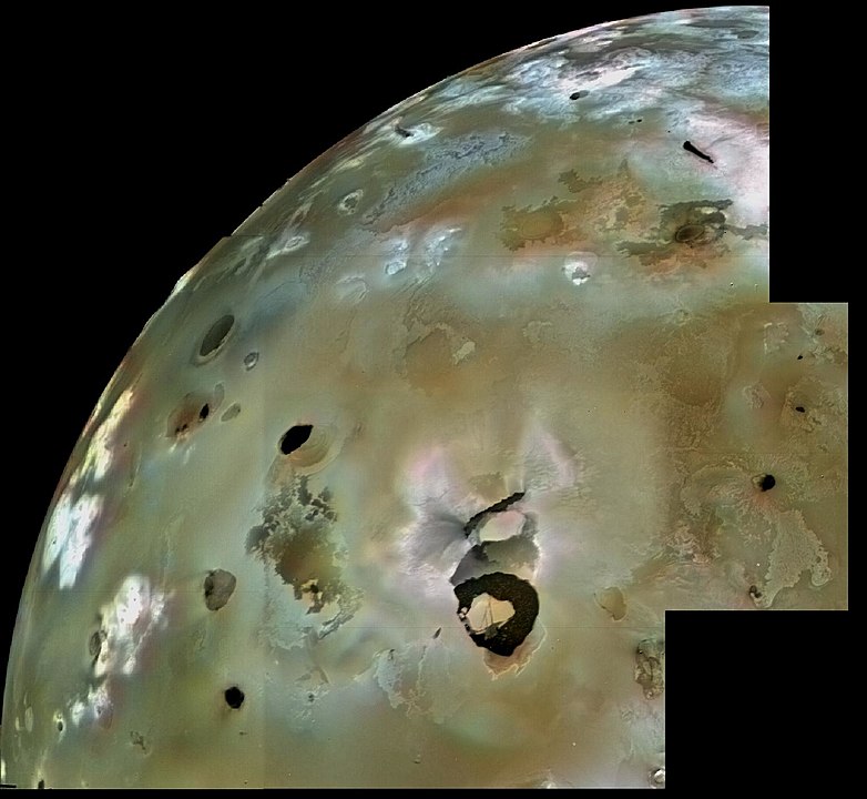 A Voyager 1 image mosaic of Loki and the surrounding surface of Io, including lava flows and volcanic pits. Numerous volcanic calderas and lava flows are visible here. Loki Patera, an active lava lake, is the large shield-shaped black feature. Image Credit: By NASA/JPL/USGS - http://photojournal.jpl.nasa.gov/catalog/PIA00320, Public Domain, https://commons.wikimedia.org/w/index.php?curid=4898984 