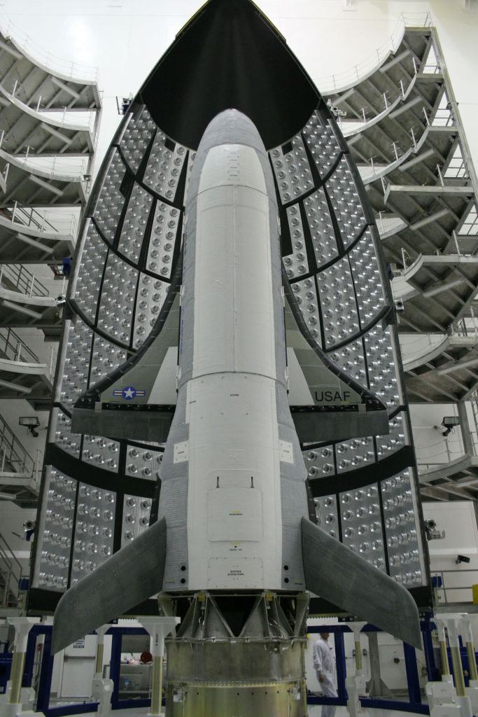The X-37B Orbital Test Vehicle waits in the encapsulation cell of the Evolved Expendable Launch vehicle April 5, 2010, at the Astrotech facility in Titusville, Fla. Half of the Atlas V five-meter fairing is visible in the background. (Courtesy photo: US Air Force)