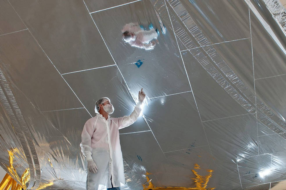 In this image an engineer is looking at one of the sun-shield's layers in a clean room. The pattern of seams helps prevent ripping. Image Credit: Nexvolve.