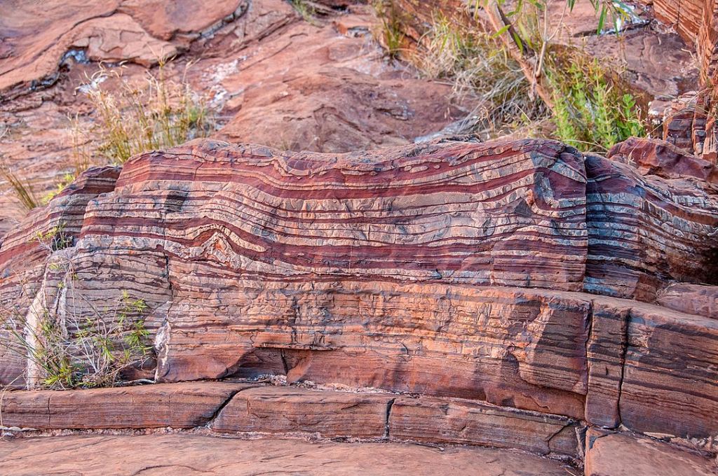 A banded iron formation in Australia. The conventional understanding is that these formed in seawater with the release of oxygen during the Great Oxygenation Event. Image Credit: By Graeme Churchard from Bristol, UK - Dales GorgeUploaded by PDTillman, CC BY 2.0, https://commons.wikimedia.org/w/index.php?curid=30889569
