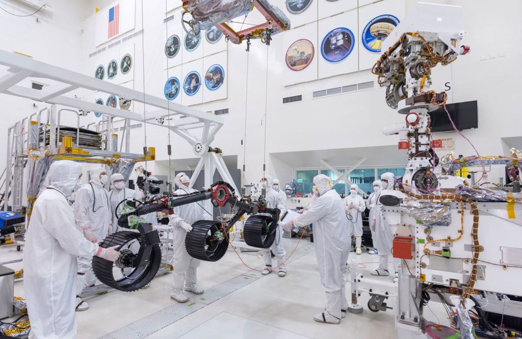 Personnel attaching the starboard leg and wheel assembly on the 2020 rover. These are engineering models, used only in testing. The flight models will be attached prior to the mission. Image Credit: NASA/JPL-Caltech