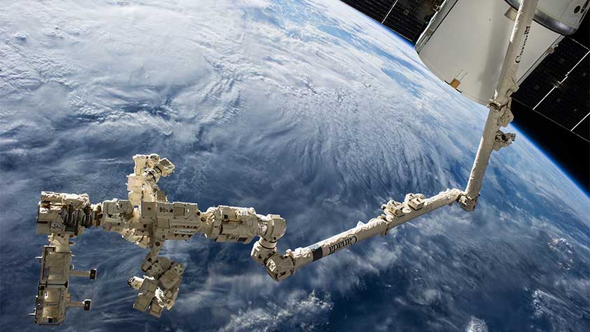 The International Space Station's Canadarm2 and Dextre carry the RapidScat instrument after removing it from the trunk of the SpaceX Dragon cargo ship (upper right). (Credit: NASA) 