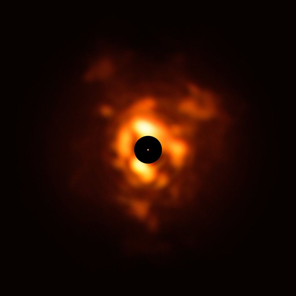 This image, obtained with the VISIR instrument on ESO’s Very Large Telescope, shows the infrared light being emitted by the dust surrounding Betelgeuse in December 2019. The clouds of dust, which resemble flames in this dramatic image, are formed when the star sheds its material back into space. The black disc obscures the star's centre and much of its surroundings, which are very bright and must be masked to allow the fainter dust plumes to be seen. The orange dot in the middle is the SPHERE image of Betelgeuse’s surface, which has a size close to that of Jupiter’s orbit. Credit: ESO/P. Kervella/M. Montargès et al.