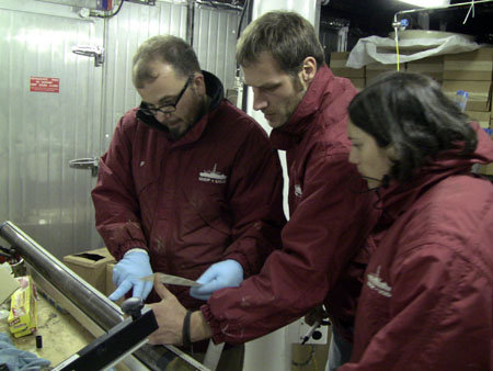 Crew members on Expedition 329 examining one of the cores. The cores are stored in a cold room first so the oxygen content can be measured. Then they're subjected to extreme pressure to squeeze the water out. Image Credit: IODP