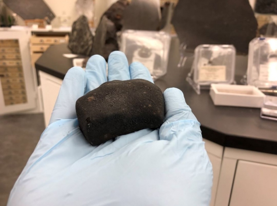 The study's lead author holds a meterorite sample that was used as part of the analysis in the paper.
