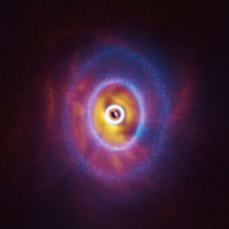 ALMA, in which ESO is a partner, and the SPHERE instrument on ESO’s Very Large Telescope have imaged GW Orionis, a triple star system with a peculiar inner region. Unlike the flat planet-forming discs we see around many stars, GW Orionis features a warped disc, deformed by the movements of the three stars at its centre. This composite image shows both the ALMA and SPHERE observations of the disc.  The ALMA image shows the disc’s ringed structure, with the innermost ring (part of which is visible as an oblong dot at the very centre of the image) separated from the rest of the disc. The SPHERE observations allowed astronomers to see for the first time the shadow of this innermost ring on the rest of the disc, which made it possible for them to reconstruct its warped shape. Image Credit: ALMA (ESO/NAOJ/NRAO), ESO/Exeter/Kraus et al.