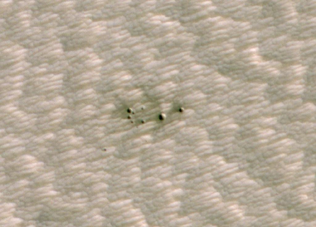 The High-Resolution Imaging Science Experiment (HiRISE) camera aboard NASA's Mars Reconnaissance Orbiter took this image of a crater cluster on Mars, the first ever to be discovered by artificial intelligence (AI). The AI first spotted the craters in images taken with the orbiter's Context Camera; scientists followed up with this HiRISE image to confirm the craters. Image Credit: NASA/JPL-Caltech/University of Arizona