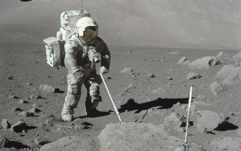 Apollo 17 astronaut Harrison Schmitt collecting a soil sample in Serenitatis basin, his spacesuit coated with dust. 