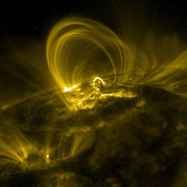 This image is an example of solar coronal loops observed by the Transition Region And Coronal Explorer (TRACE). These loops have a temperature of approximately 106 K. These loops contrast greatly with the cool chromosphere below. Image Credit: By NASA Public Domain
