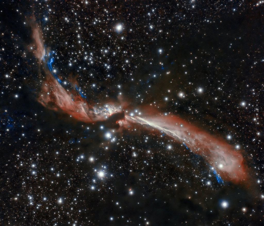 The sinuous young stellar jet, MHO 2147, meanders lazily across a field of stars in this image captured from Chile by the international Gemini Observatory, a Program of NSF's NOIRLab. The stellar jet is the outflow from a young star that is embedded in an infrared dark cloud. Astronomers suspect its sidewinding appearance is caused by the gravitational attraction of companion stars. These crystal-clear observations were made using the Gemini South telescope’s adaptive optics system, which helps astronomers counteract the blurring effects of atmospheric turbulence. Image Credit: International Gemini Observatory/NOIRLab/NSF/AURA