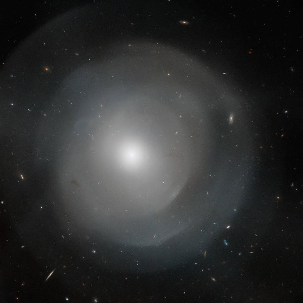 The central region of the giant elliptical galaxy NGC 474. It's set against a backdrop of more distant galaxies. Will the Milky Way resemble this galaxy in the distant future? This image was taken using the Hubble Advanced Camera for Surveys, and includes data from the Wide Field and Planetary Camera 3. (Courtesy NASA/STScI.)