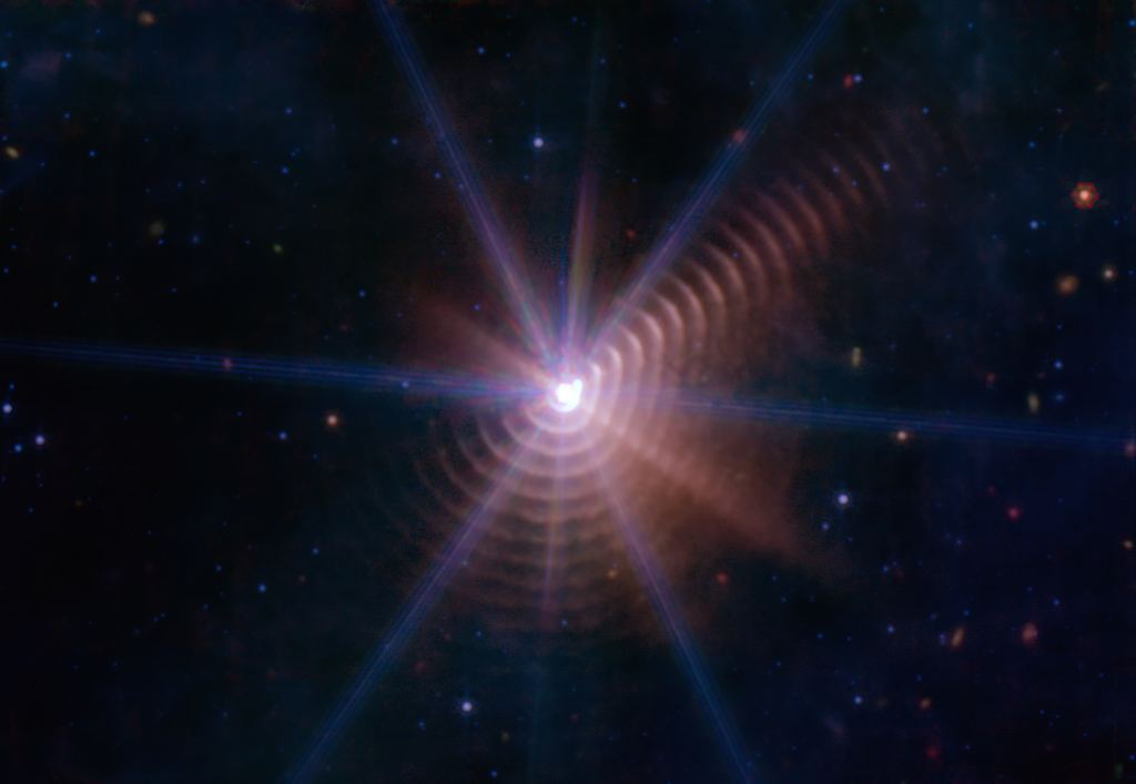 This is a JWST image of another Wolf-Rayet star, WR 140, a part of a binary pair of stars. The rings in this image are episodic ejections of dust from the star. WR 140 is a prototypical example of cosmic dust production. Image Credit: By NASA, ESA, CSA JWST MIRI & Ryan Lau et al.; Processed by Meli thev - Own work, CC BY-SA 4.0, https://commons.wikimedia.org/w/index.php?curid=121325992