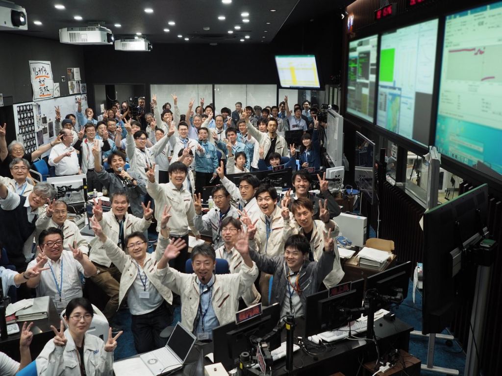 Zeigen Sie Ihren zufriedenen JAXA-Mitarbeitern "Fünfte" Zeichen des Sieges, nachdem Hayabusa 2 erfolgreich Proben vom Asteroiden Ryugu gesammelt hat.  Bildnachweis: JAXA