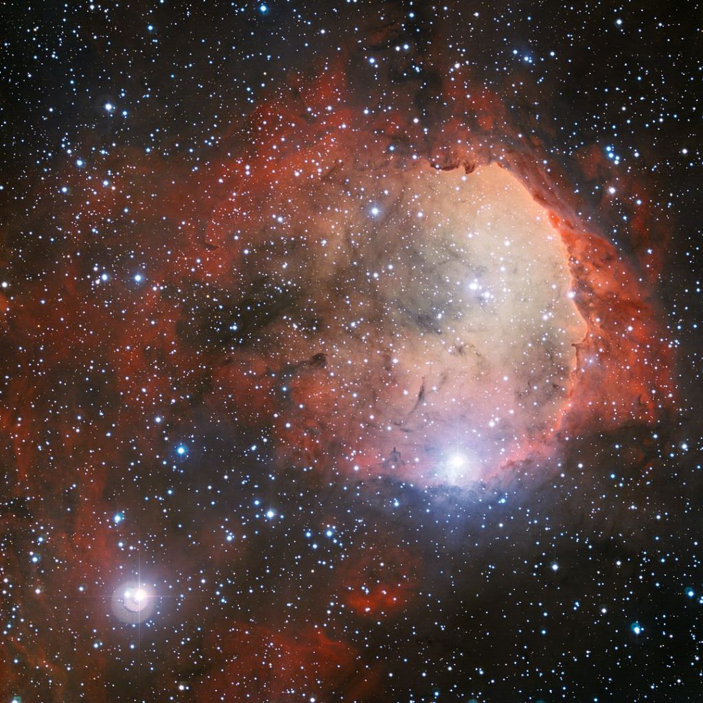 This is an image of NGC 3324 from the ESO's 2.2-metre telescope at the La Silla Observatory. It shows the intense radiation from several of NGC 3324's massive, blue-white stars and how they've carved out a cavity in the surrounding gas and dust. The ultraviolet radiation from these young hot stars also causes the gas cloud to glow in rich colours. Image Credit: By ESO - http://www.eso.org/public/images/eso1207a/, CC BY 4.0, https://commons.wikimedia.org/w/index.php?curid=27850385