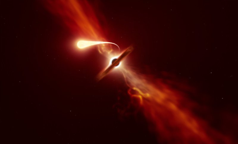 This illustration depicts a star (in the foreground) experiencing spaghettification as it’s sucked in by a supermassive black hole (in the background) during a 'tidal disruption event'. Credit: ESO/M. Kornmesser