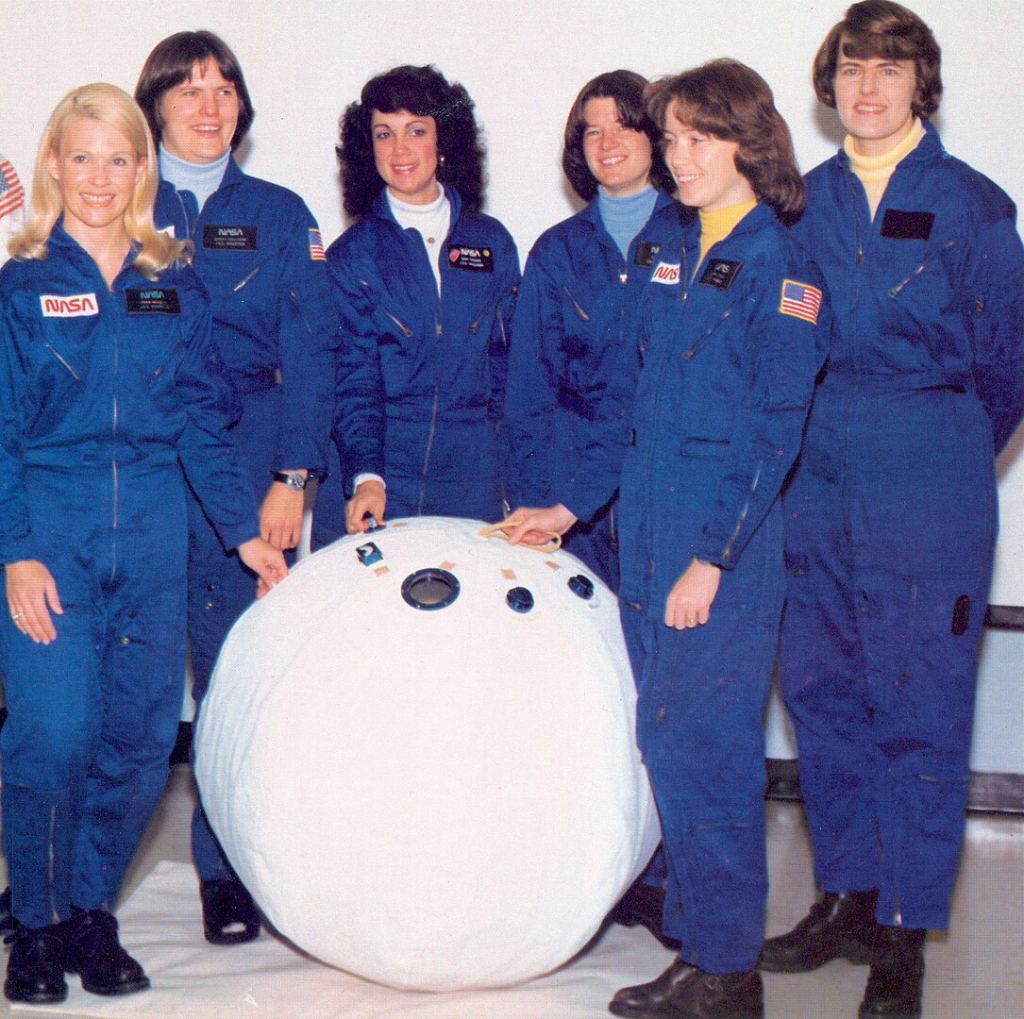 These trailblazing women are the first six female NASA astronauts, shown with the PRE. Maybe they were smiling because they knew the PRE was abandoned and they'd never have to curl up inside it. From left to right: Margaret R. (Rhea) Seddon, Kathryn D. Sullivan, Judith A. Resnik (RIP), Sally K. Ride (RIP), Anna L. Fisher, and Shannon W. Lucid.