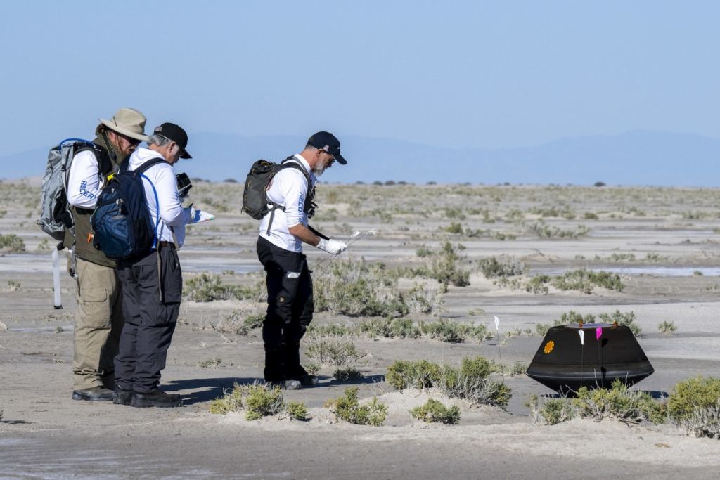 Lauretta, right, and NASA Astromaterials Curator Francis McCubbin and NASA Sample Return Capsule Science Lead Scott Sandford approach the capsule in this image. Detailed observations of the capsule, even at this early stage, could be important later. Image Credit: NASA/Keegan Barber