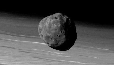 The ESA's Mars Express orbiter captured this image of Phobos over the Martian landscape in this image taken in November 2010. Irregularly shaped and only 27 km long, Phobos is actually much darker (due to its carbon-rich surface) than is apparent in this contrast-enhanced view. Image Credit: ESA / DLR / G. neukum