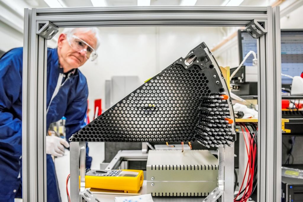 This image shows Stu Harris working on assembling the focal plane for the Dark Energy Spectroscopic Instrument (DESI) at Lawrence Berkeley National Laboratory in 2017 in Berkeley, Calif. Ten petals, each containing 500 robotic positioners that are used to gather light from targeted galaxies, form the complete focal plane. DESI is attached to the 4-meter Mayall Telescope at Kitt Peak National Observatory. Image Credit: DESI/NSF NOIRlab