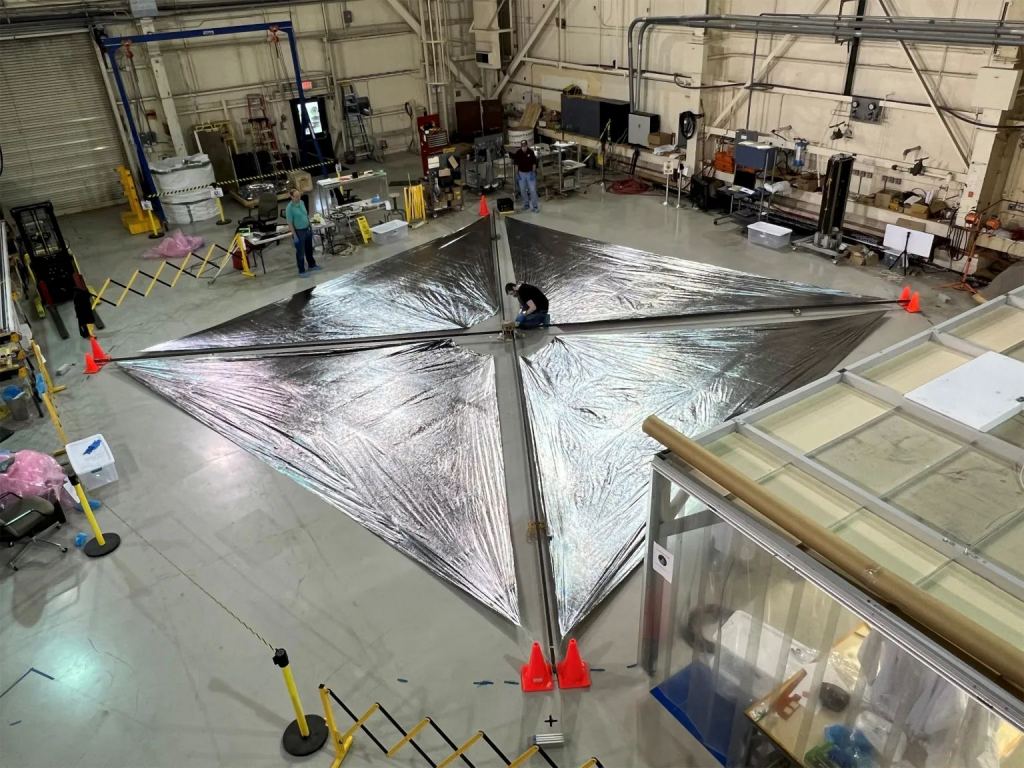 Questa immagine mostra l'ACS3 mentre viene spiegato al Langley Research Center della NASA.  Il vento solare è affidabile ma non molto potente.  Richiede un'ampia superficie velica per alimentare efficacemente un veicolo spaziale.  L'ACS2 è lungo circa 9 metri (30 piedi) per lato e richiede un sistema di bracci robusto e leggero.  Credito immagine: NASA